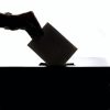 Silhouette of voter placing ballot in ballot box.
