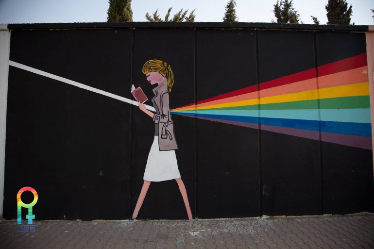 Kurdistan LGBTQ mural showing a woman reading and refracting white light into a rainbow